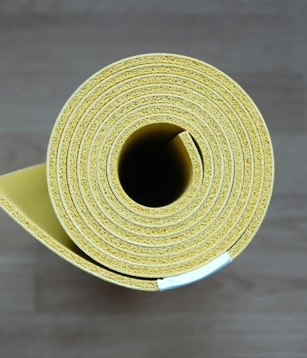 Close-up of a yoga mat rolled out on a wooden floor next to a window.