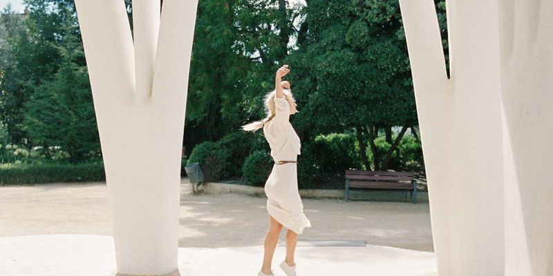 Person performing a graceful, flowing movement in a bright, open space.